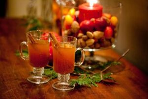 Cozy fall setup with hot apple cider, blankets, pumpkins, and candlelight by the fireplace.